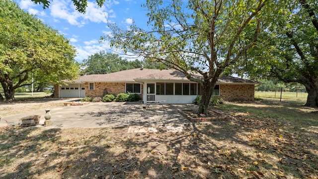 ranch-style home with a sunroom, brick siding, and an attached garage