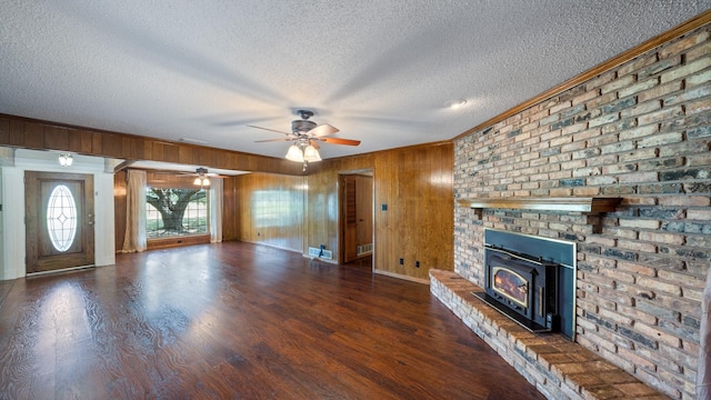 unfurnished living room featuring a textured ceiling, wooden walls, ornamental molding, and wood finished floors