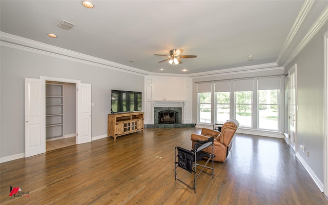 living room featuring dark wood-type flooring, a fireplace, visible vents, baseboards, and crown molding