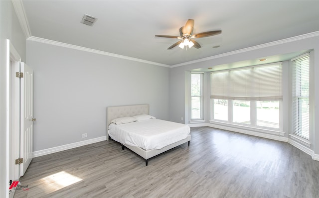 unfurnished bedroom with visible vents, crown molding, baseboards, and wood finished floors