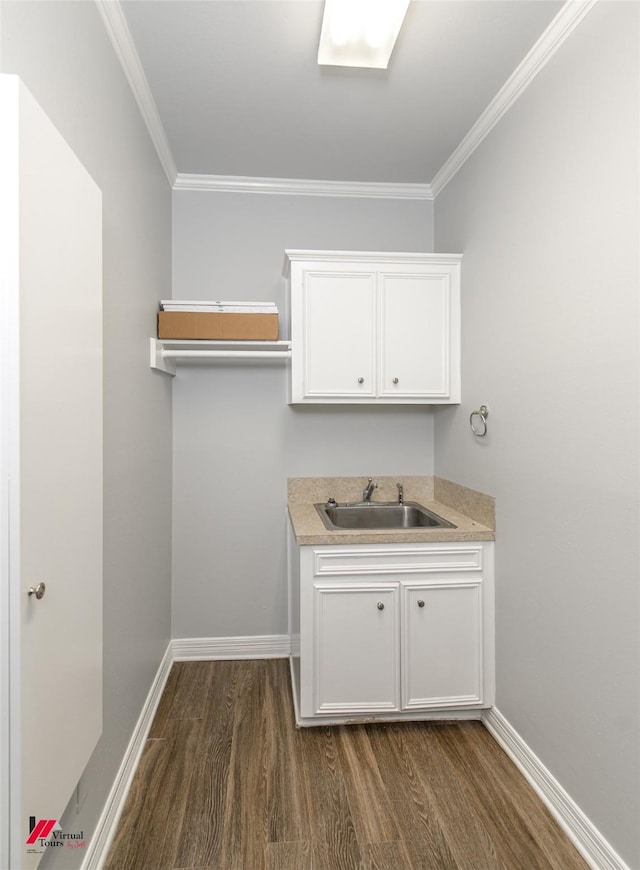 laundry room featuring dark wood-style floors, ornamental molding, a sink, and baseboards