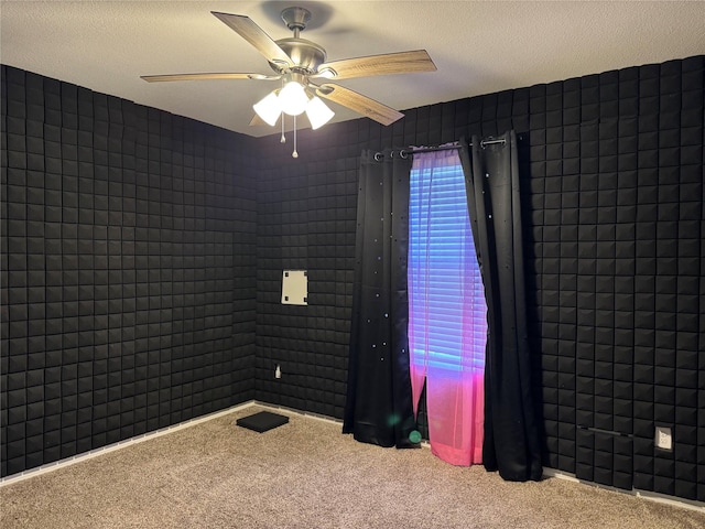 carpeted spare room featuring a textured ceiling and a ceiling fan