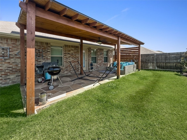 rear view of house with brick siding, a patio, outdoor lounge area, a lawn, and fence