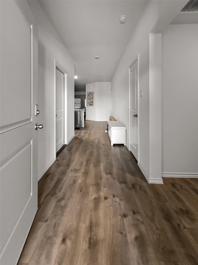 hallway featuring dark wood-style flooring and baseboards