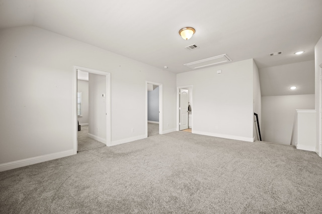 spare room featuring light carpet and vaulted ceiling