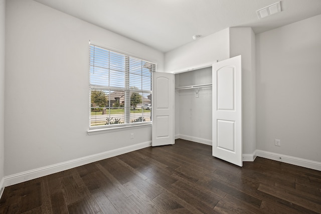 unfurnished bedroom featuring a closet and dark hardwood / wood-style floors