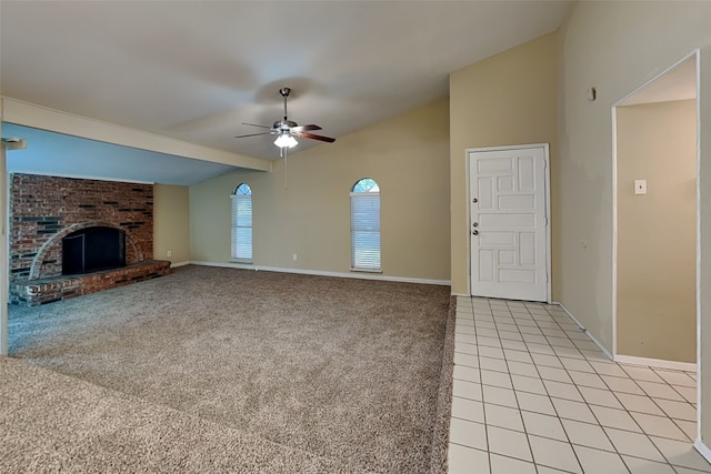 unfurnished living room with vaulted ceiling, brick wall, a fireplace, light tile patterned floors, and ceiling fan