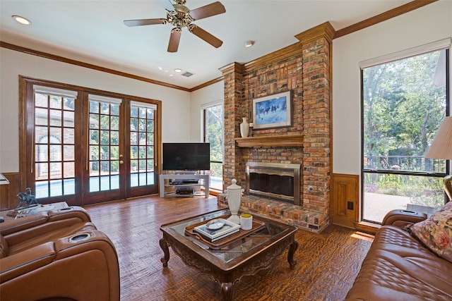 living room featuring ceiling fan, french doors, a brick fireplace, crown molding, and hardwood / wood-style floors