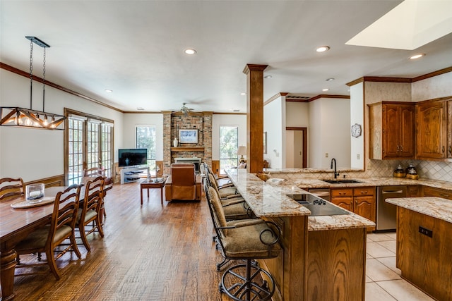 kitchen with ceiling fan, sink, hanging light fixtures, a breakfast bar area, and light wood-type flooring