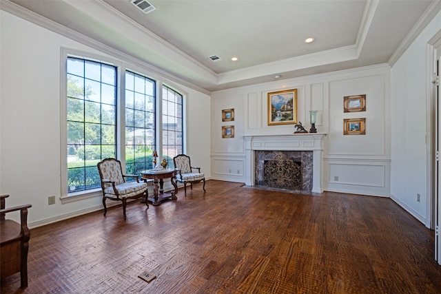 sitting room with dark hardwood / wood-style flooring, a premium fireplace, crown molding, and a tray ceiling