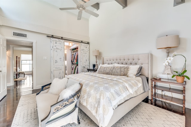 bedroom featuring wood-type flooring, a closet, a spacious closet, ceiling fan, and a barn door