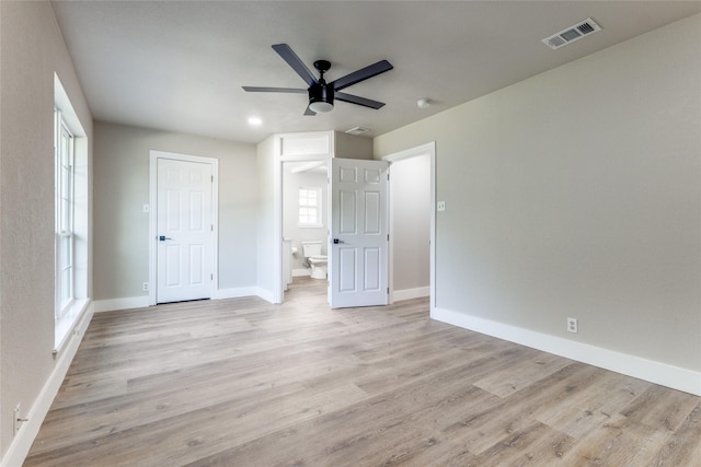 unfurnished bedroom with ensuite bathroom, light wood-type flooring, and ceiling fan