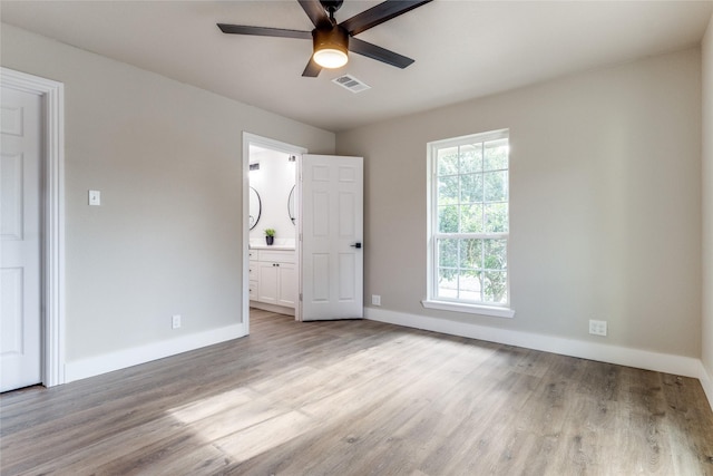 unfurnished bedroom with ensuite bathroom, ceiling fan, and light hardwood / wood-style floors