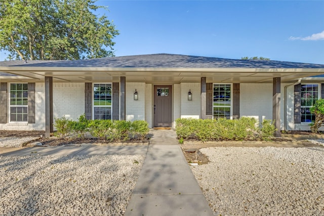 single story home featuring covered porch, brick siding, and roof with shingles