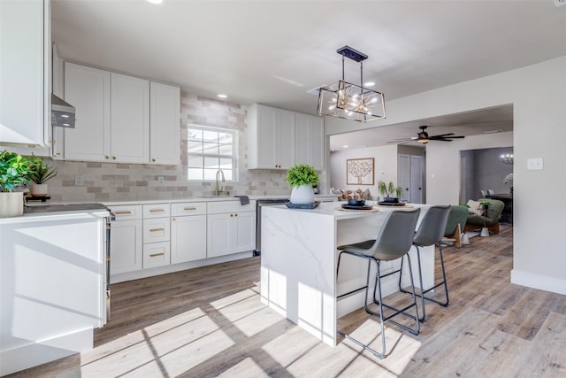 kitchen with a center island, pendant lighting, sink, white cabinets, and ceiling fan with notable chandelier