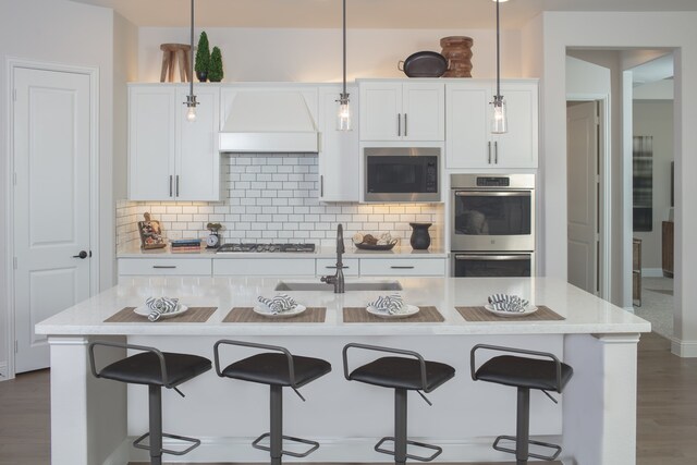 kitchen featuring pendant lighting, sink, a kitchen island with sink, and stainless steel appliances