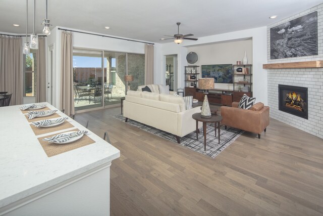 living room with ceiling fan, dark hardwood / wood-style flooring, and a brick fireplace