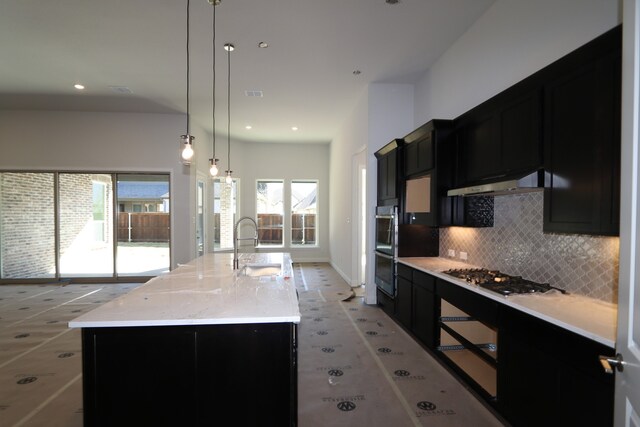 kitchen featuring a center island with sink, sink, hanging light fixtures, and a wealth of natural light