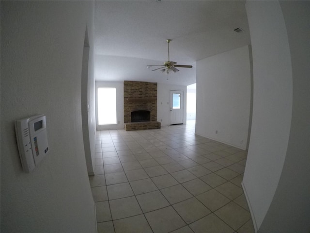 unfurnished living room featuring ceiling fan, a fireplace, vaulted ceiling, and light tile patterned floors