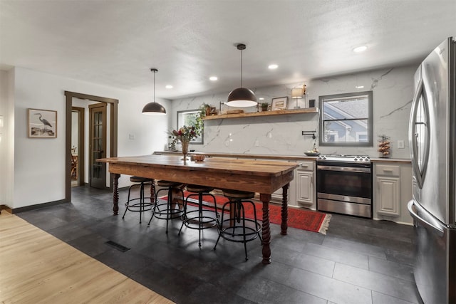 kitchen featuring dark hardwood / wood-style floors, pendant lighting, white cabinets, a textured ceiling, and stainless steel appliances