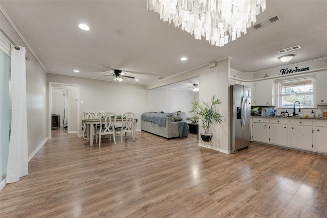 interior space with a textured ceiling, sink, ceiling fan with notable chandelier, light hardwood / wood-style flooring, and crown molding