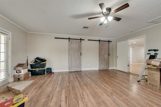 miscellaneous room with light hardwood / wood-style floors, crown molding, ceiling fan, and a barn door