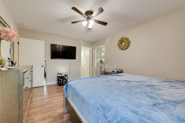 bedroom featuring light hardwood / wood-style flooring, ceiling fan, and a textured ceiling