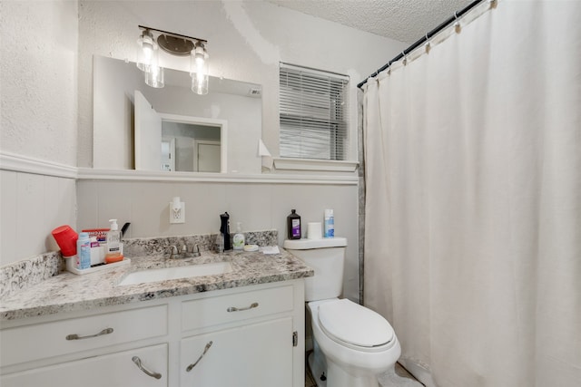 bathroom with vanity, toilet, and a textured ceiling