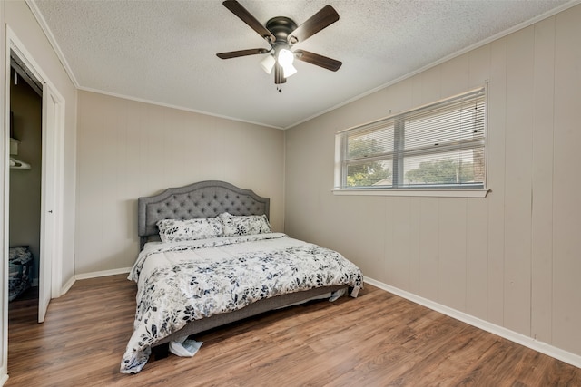 bedroom featuring ceiling fan, hardwood / wood-style flooring, wooden walls, and ornamental molding