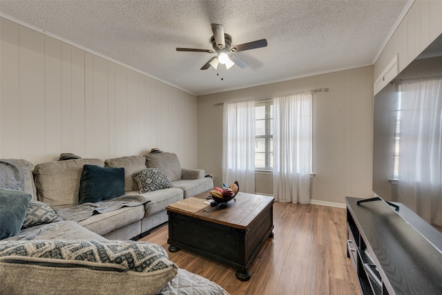 living room with a textured ceiling, wood-type flooring, crown molding, and ceiling fan