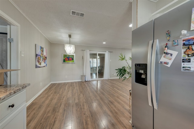 kitchen featuring white cabinets, a textured ceiling, hardwood / wood-style flooring, and stainless steel fridge with ice dispenser