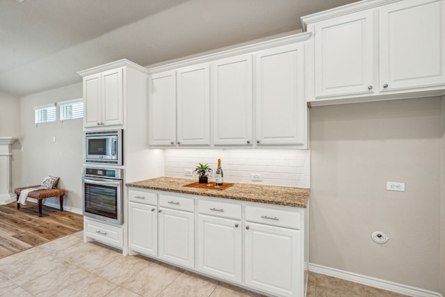 kitchen featuring light wood-type flooring, appliances with stainless steel finishes, backsplash, and white cabinetry