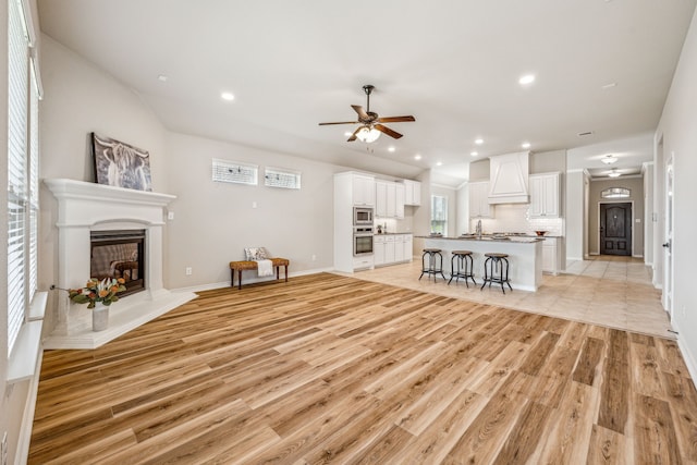 unfurnished living room with ceiling fan, sink, and light hardwood / wood-style floors