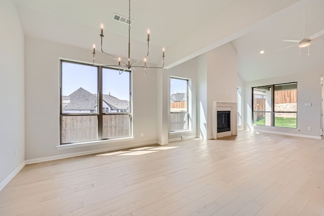 unfurnished living room featuring light hardwood / wood-style floors, high vaulted ceiling, and ceiling fan with notable chandelier