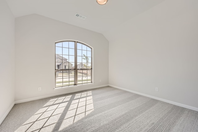 carpeted empty room featuring lofted ceiling