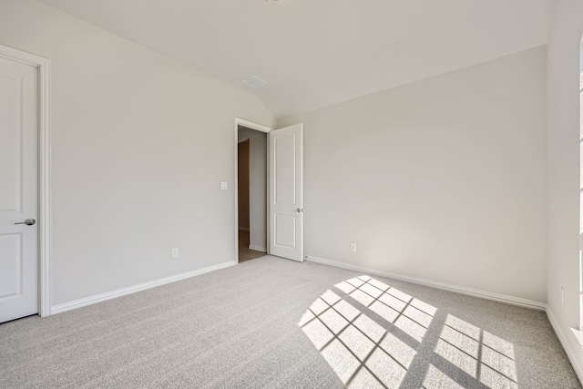 empty room with vaulted ceiling and light colored carpet