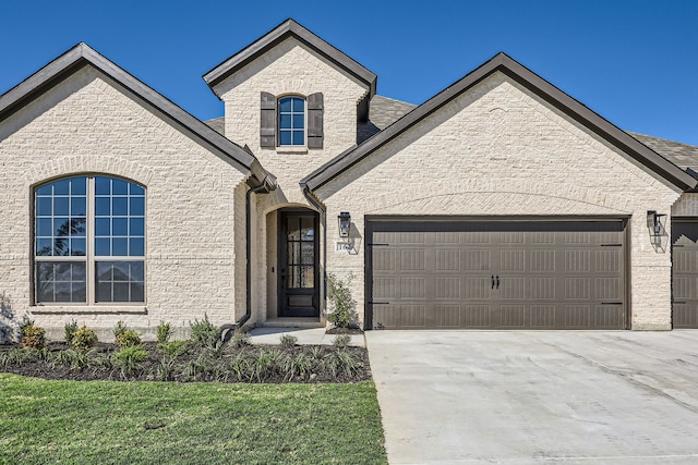 french provincial home with a front lawn and a garage