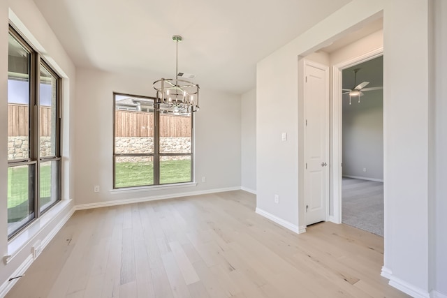 unfurnished dining area featuring light wood-type flooring and ceiling fan with notable chandelier