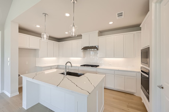 kitchen featuring light hardwood / wood-style floors, white cabinets, sink, and a center island with sink