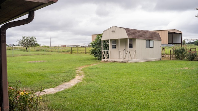 view of yard featuring a storage unit, a rural view, an outdoor structure, and fence