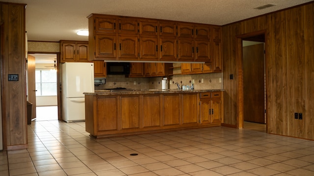 kitchen featuring ornamental molding, black microwave, tasteful backsplash, and white refrigerator