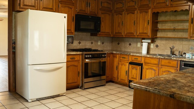 kitchen with light tile patterned flooring, backsplash, stainless steel gas range, and white refrigerator