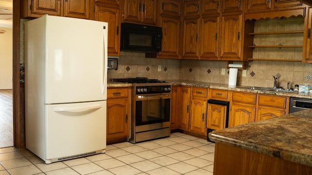 kitchen featuring brown cabinets, light tile patterned floors, freestanding refrigerator, stainless steel gas stove, and black microwave