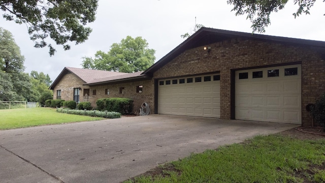 ranch-style home with a garage, a front yard, concrete driveway, and brick siding