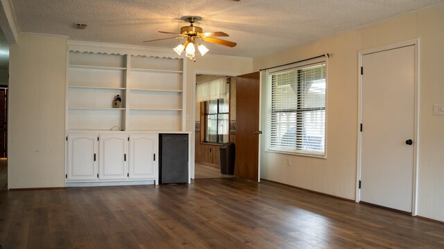 unfurnished living room featuring a wealth of natural light, ceiling fan, a textured ceiling, and dark hardwood / wood-style flooring