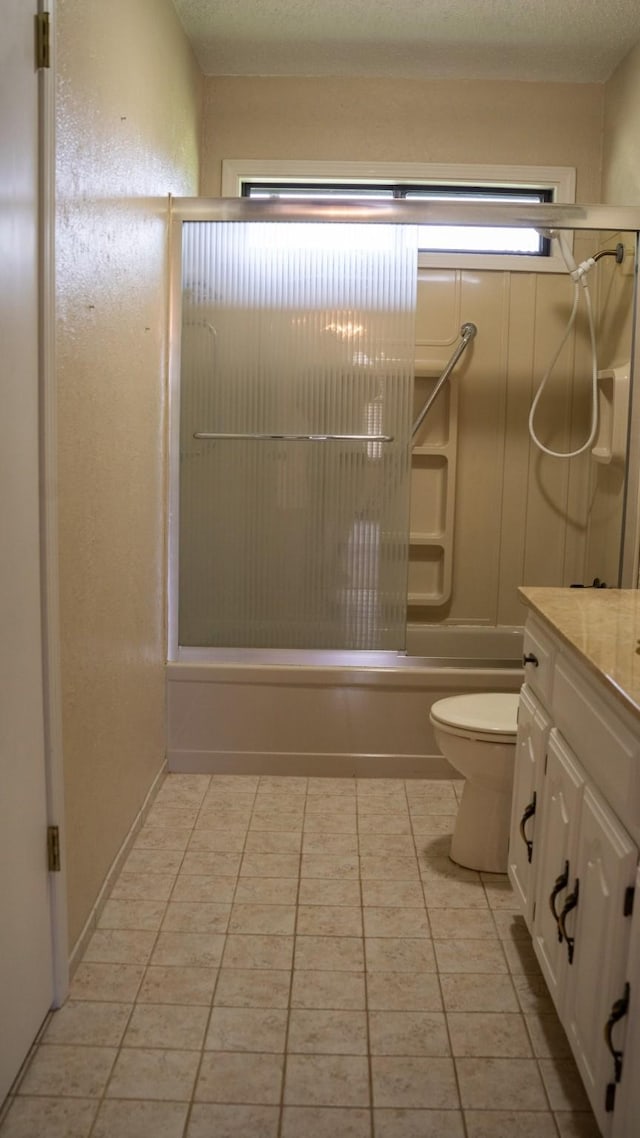 bathroom with a textured ceiling, shower / bath combination with glass door, tile patterned flooring, and toilet