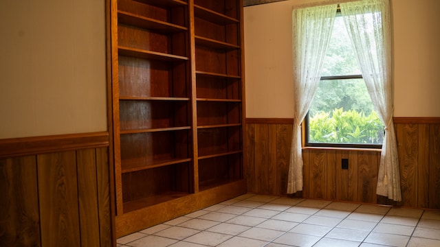 tiled spare room featuring wooden walls