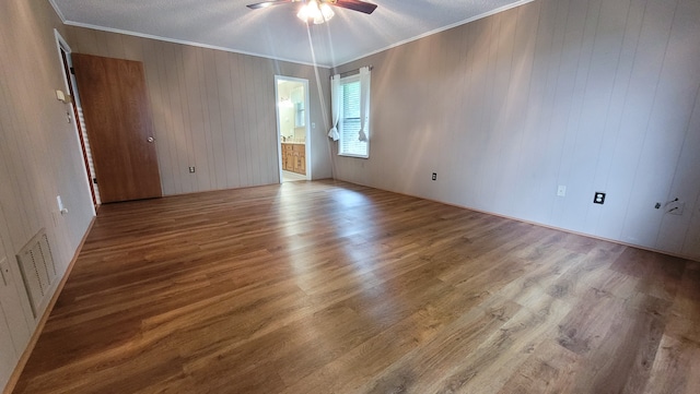 unfurnished room featuring hardwood / wood-style floors, ornamental molding, ceiling fan, and a textured ceiling