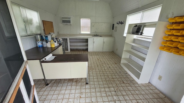 kitchen featuring dark countertops, an AC wall unit, white cabinets, and light floors