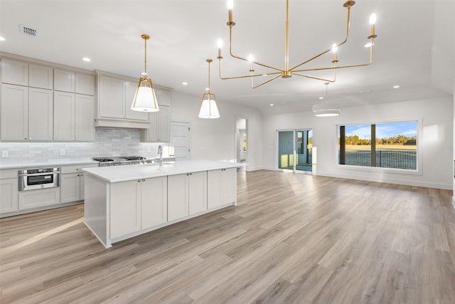 115 Palisades Dr, Gordonville, TX 76245 - kitchen with pendant lighting, backsplash, light hardwood / wood-style flooring, and an island with sink